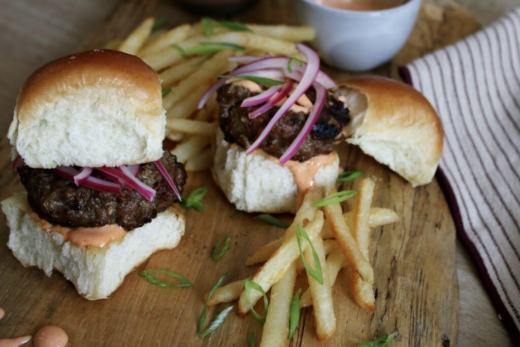 burger sliders with fries on cutting board