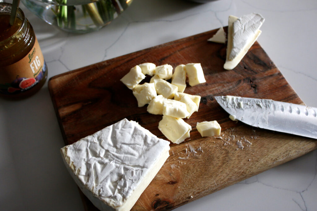 brie cut into bite size pieces on a cutting board